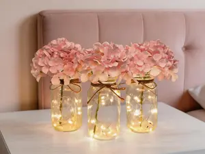 3-piece mason jar set with built-in lights and blush hydrangea accents. Decorative jars double as flower vases, serving as farmhouse-style table centerpieces for home, wedding and party decor.