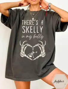 Comfort Colors There’s A Skelly In My Belly Halloween Shirt – Funny Pregnancy Announcement Tee with Skeleton Hands and Baby Skeleton Design for Expecting Moms