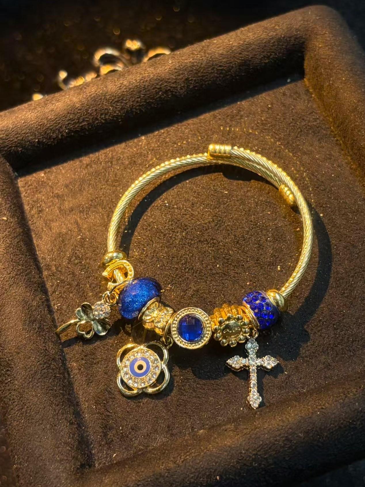 Women's Gold-Tone Open Cable Charm Bangle, Stackable Costume Jewelry Bracelet with Evil Eye, 4-Leaf Clover, Cross, Sparkling Blue Crystal Beads Charms