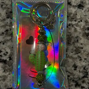 The Oasis Charm Keychain with Green Polka Dot Bug and Beaded Accents in Holographic Packaging