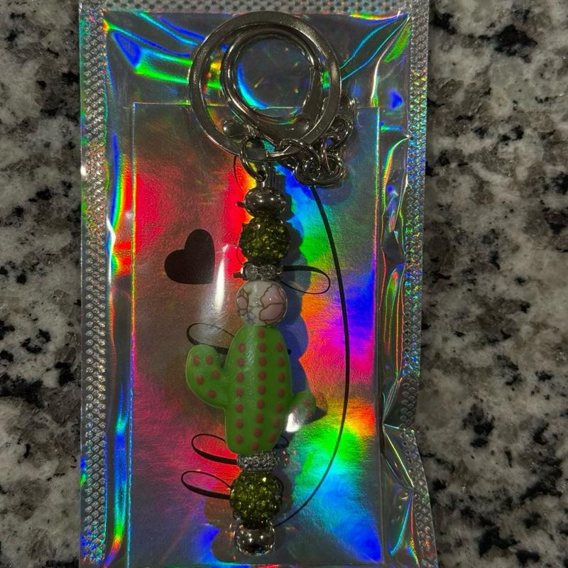 The Oasis Charm Keychain with Green Polka Dot Bug and Beaded Accents in Holographic Packaging