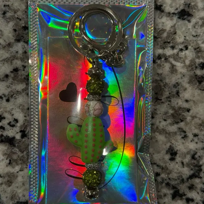 The Oasis Charm Keychain with Green Polka Dot Bug and Beaded Accents in Holographic Packaging