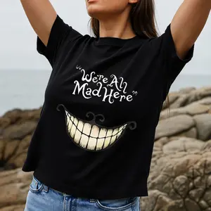 Whimsical Gothic Style Women's T-Shirt With Cheshire Cat Smile And Quote We're All Mad Here Perfect For Halloween Or Casual Wear Ideal Gift For Alice In Wonderland Fans