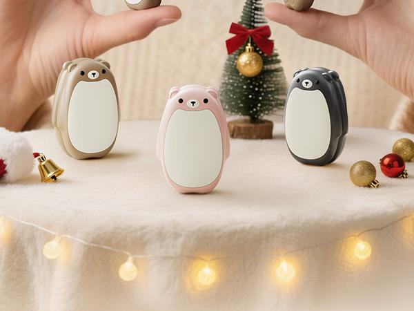 Three bear-shaped hand warmers in beige, pink and black