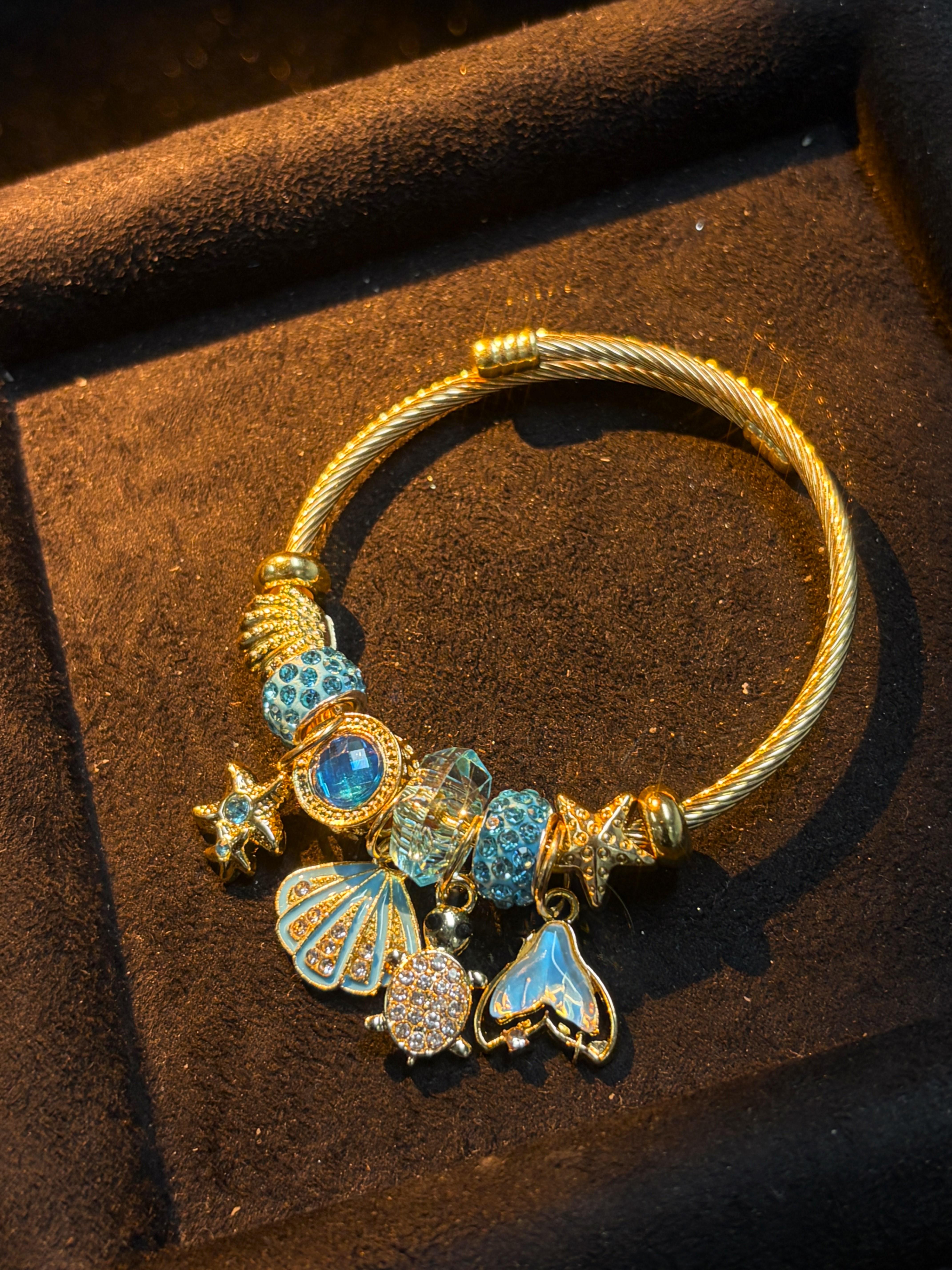 Women's Gold-Tone Ocean Theme Charm Bangle - Sea Shell, Turtle, Starfish, Mermaid Tail Accents with Sparkling Blue Crystal Beads Women's Gold-Tone Ocean Theme Charm Bangle - Sea Shell, Turtle, Starfish, Mermaid Tail Accents with Sparkling Blue Crystal Beads