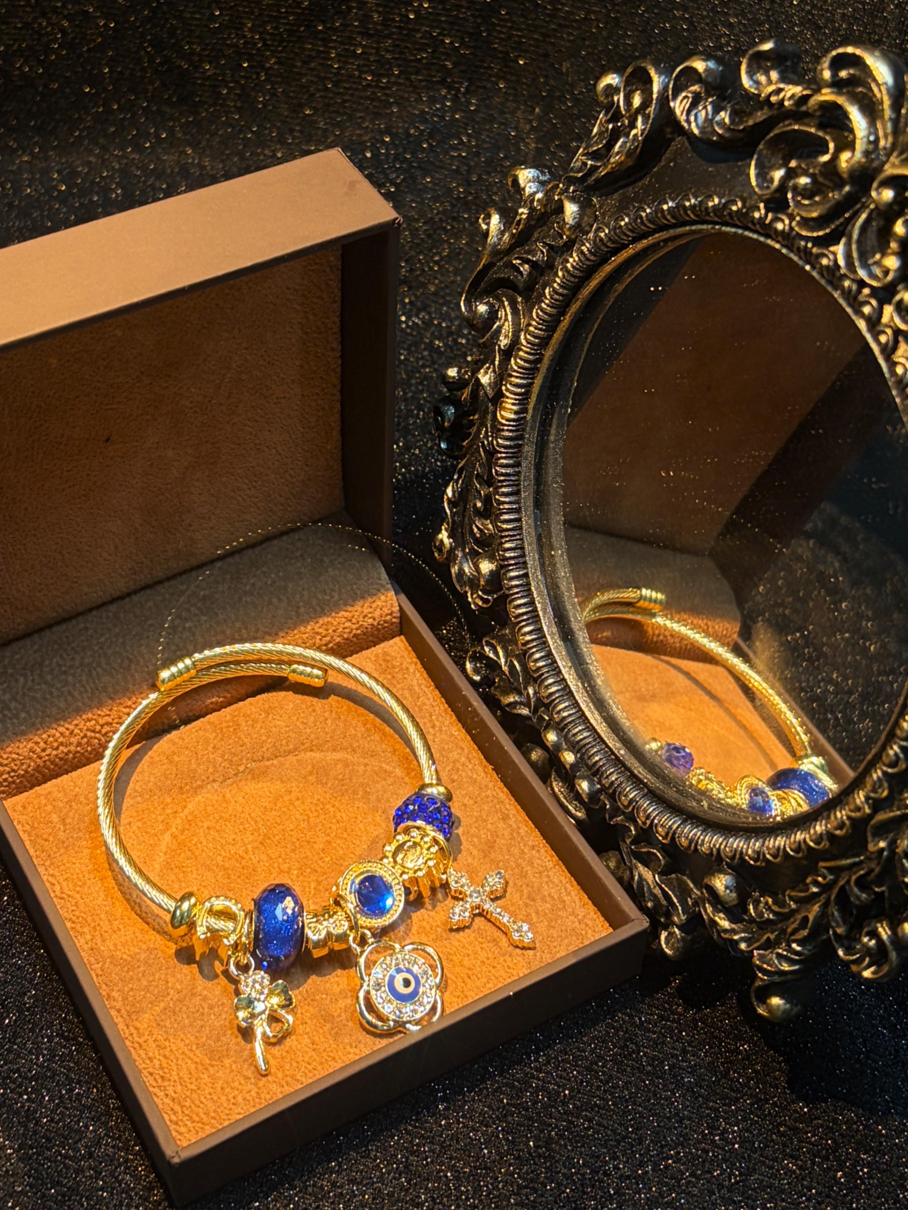 Women's Gold-Tone Open Cable Charm Bangle, Stackable Costume Jewelry Bracelet with Evil Eye, 4-Leaf Clover, Cross, Sparkling Blue Crystal Beads Charms Women's Gold-Tone Open Cable Charm Bangle, Stackable Costume Jewelry Bracelet with Evil Eye, 4-Leaf Clover, Cross, Sparkling Blue Crystal Beads Charms