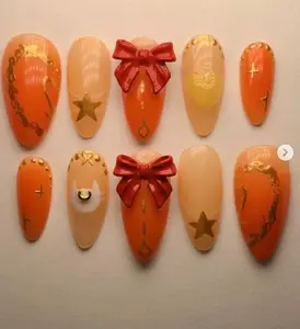 cute orange and gold press on nails with 3d red bows, star accents, heart motifs and delicate chain details for a sweet magical girl inspired nail art set