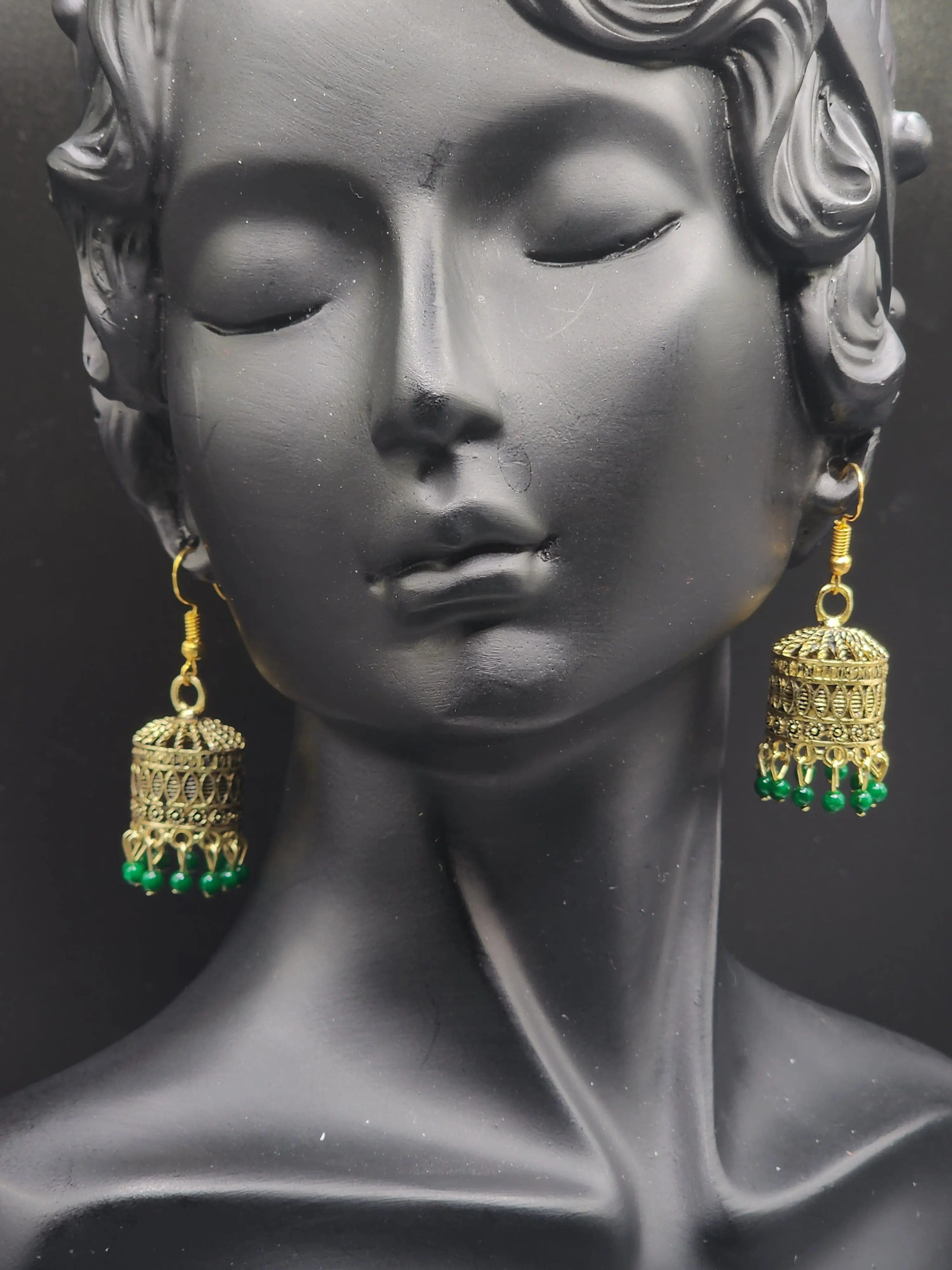 Pskelegance presents these exquisite gold jhumkas, adorned with emerald green drops.