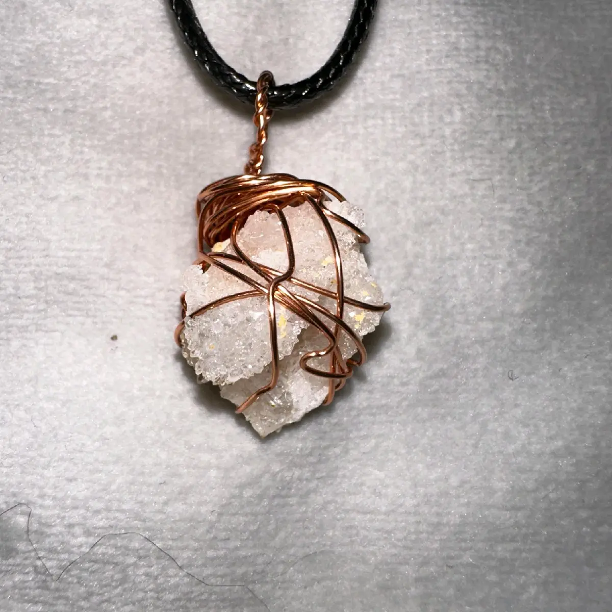 Quartz broken off from a geode, set in broze wire with complementary black leather chain.
