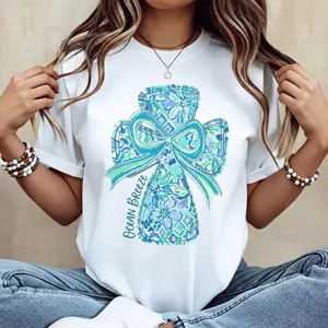 Cotton casual round-neck short-sleeve summer T-shirt with vibrant cross and bow design “He Is Risen” printed graphic tee machine washable not dry cleanable made in USA Long lasting durable print casual tee top