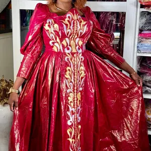 A Gorgeous Deep Red Bazin Gown with Glossy Finish Intricate Gold White and Blue Embroidery Puffed Sleeves Structured Bodice Full Skirt Regal Flattering Silhouette Effortless Elegance