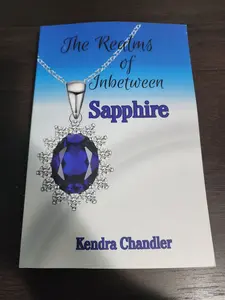 Book and one book mark from the book The Realms of Inbetween Sapphire blue font