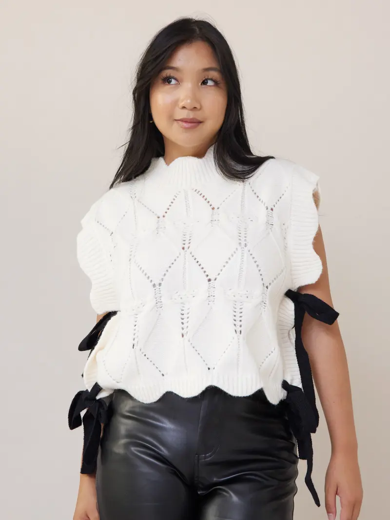 Wishlist Vest - White comfy cable knit sweater vest with scallop details, black side bows, and a turtleneck, offering a slightly oversized fit