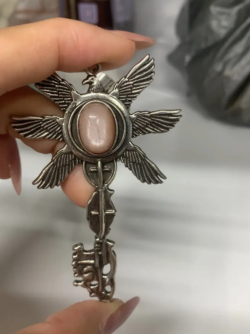 Candice(16225)gc.A stunning orange moonstone pendant with intricate silver wings, glowing softly like captured twilight. Its ethereal hue and detailed craftsmanship evoke mystery and elegance.
