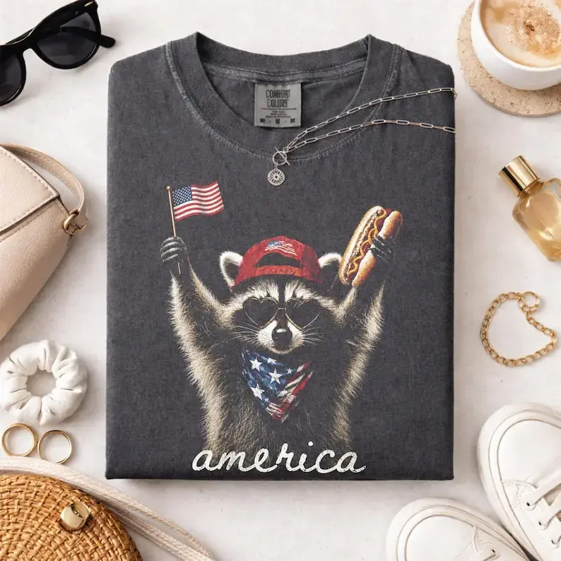 [Sale Up To 50%] Comfort Colors America Raccoon Hot Dog T Shirt, Kids 4th of July Raccoon TShirt, Patriotic American Flag Graphic Tee, Women's Retro USA Animal T-Shirt - Rock Rolla