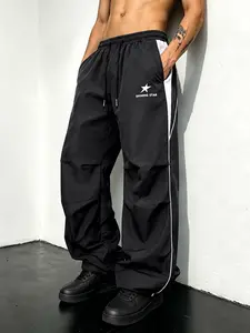 Men’s black-and-white colorblock parachute pants with star print; street functional style; athletic style; elastic waistband; minimalist relaxed fit; mature commuter style; versatile for everyday wear; streetwear brand–style black star-print functional ca