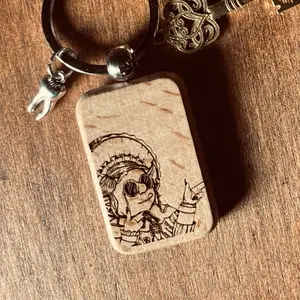 Granny’s Wealth Charm Keychain. Wood engraved with a portrait of Granny Goblin. Completed with a silvered tooth